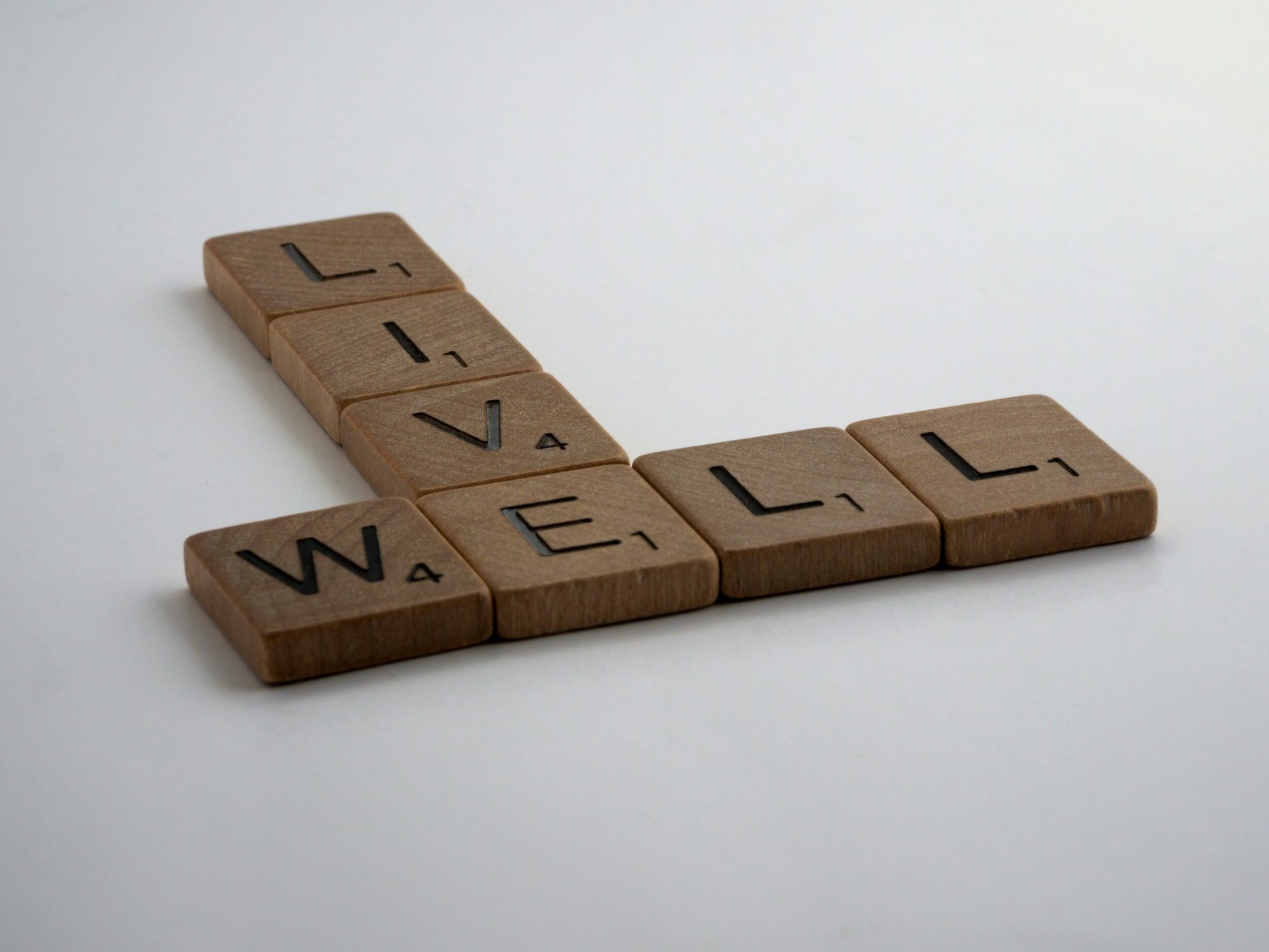 Wooden letter tiles spelling LIVE and WELL