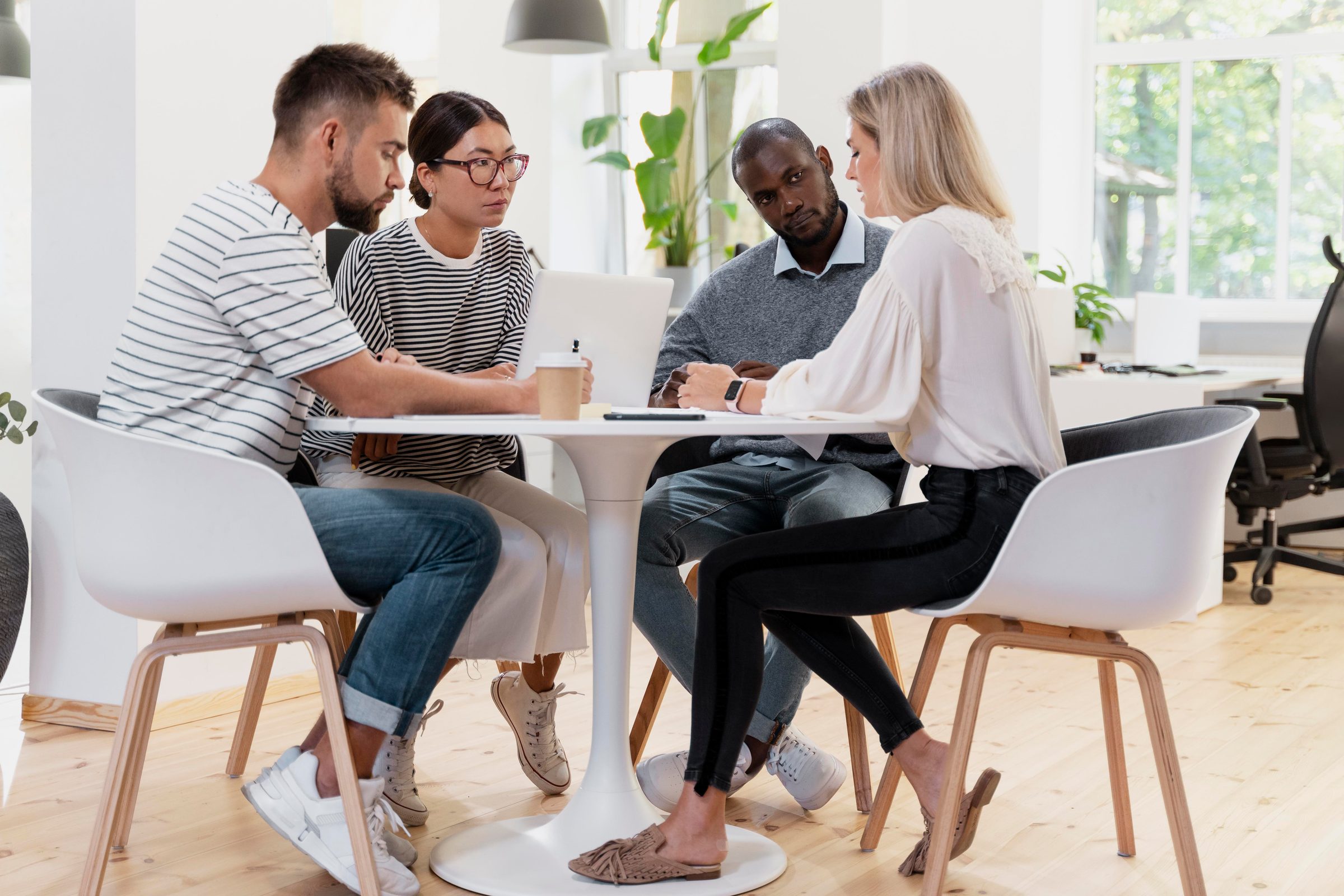 Four colleagues talking around a small round table in a bright room
