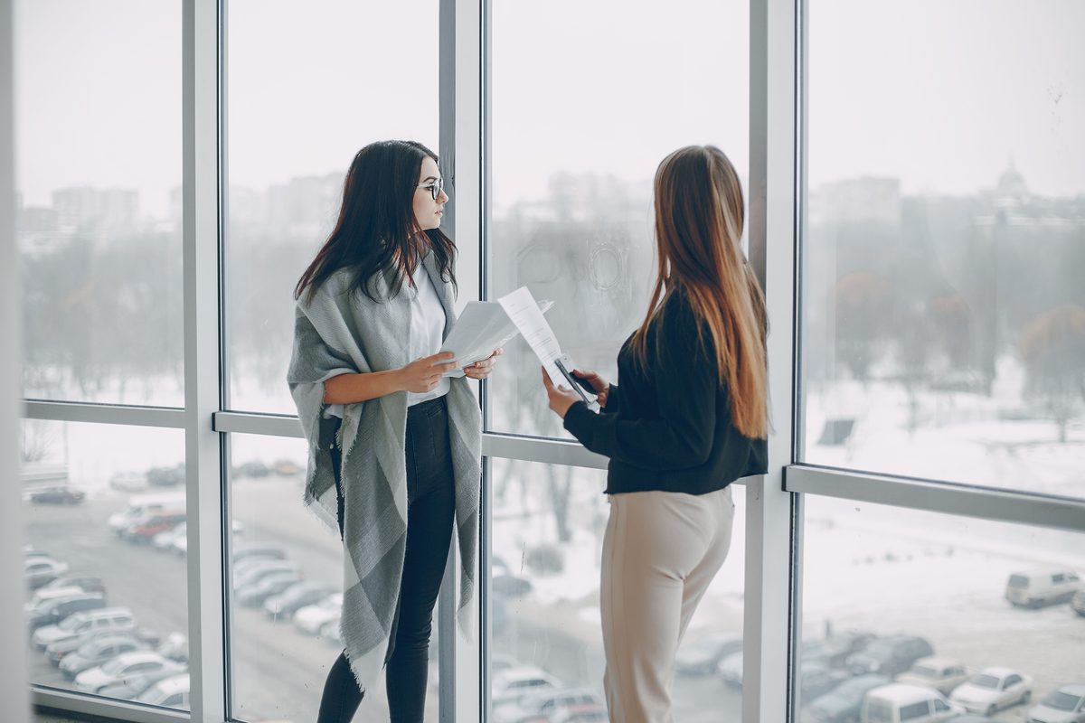 Two colleagues talking by a tall window