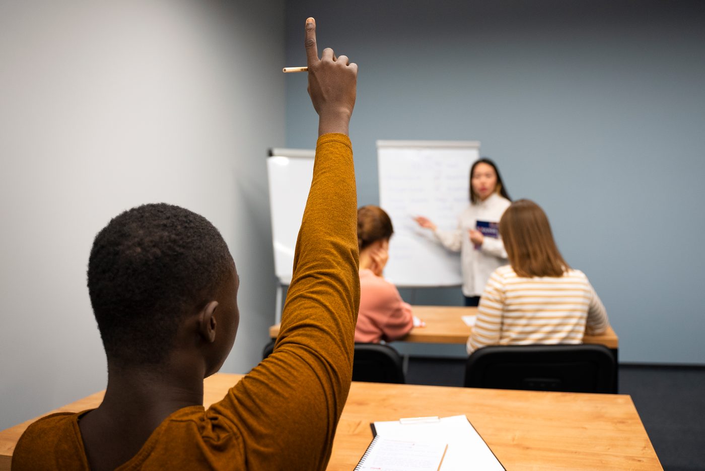 A participant raising a hand while a trainer stands at a flipchart