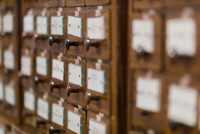 A wall of wooden card-index drawers with brass pulls and handwritten labels